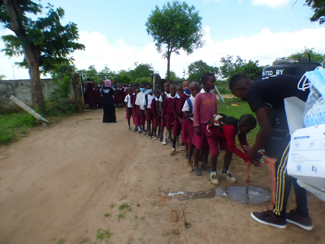 Students of Ngiluni Comprehensive School preparing for a guiding and counseling session by washing hands and wearing face masks.