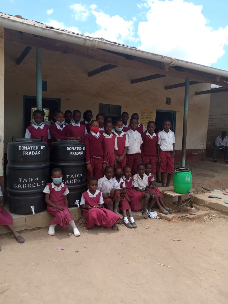 Students in Ngiluni Comprehensive School receive water tanks donated by FRADAKI members. 