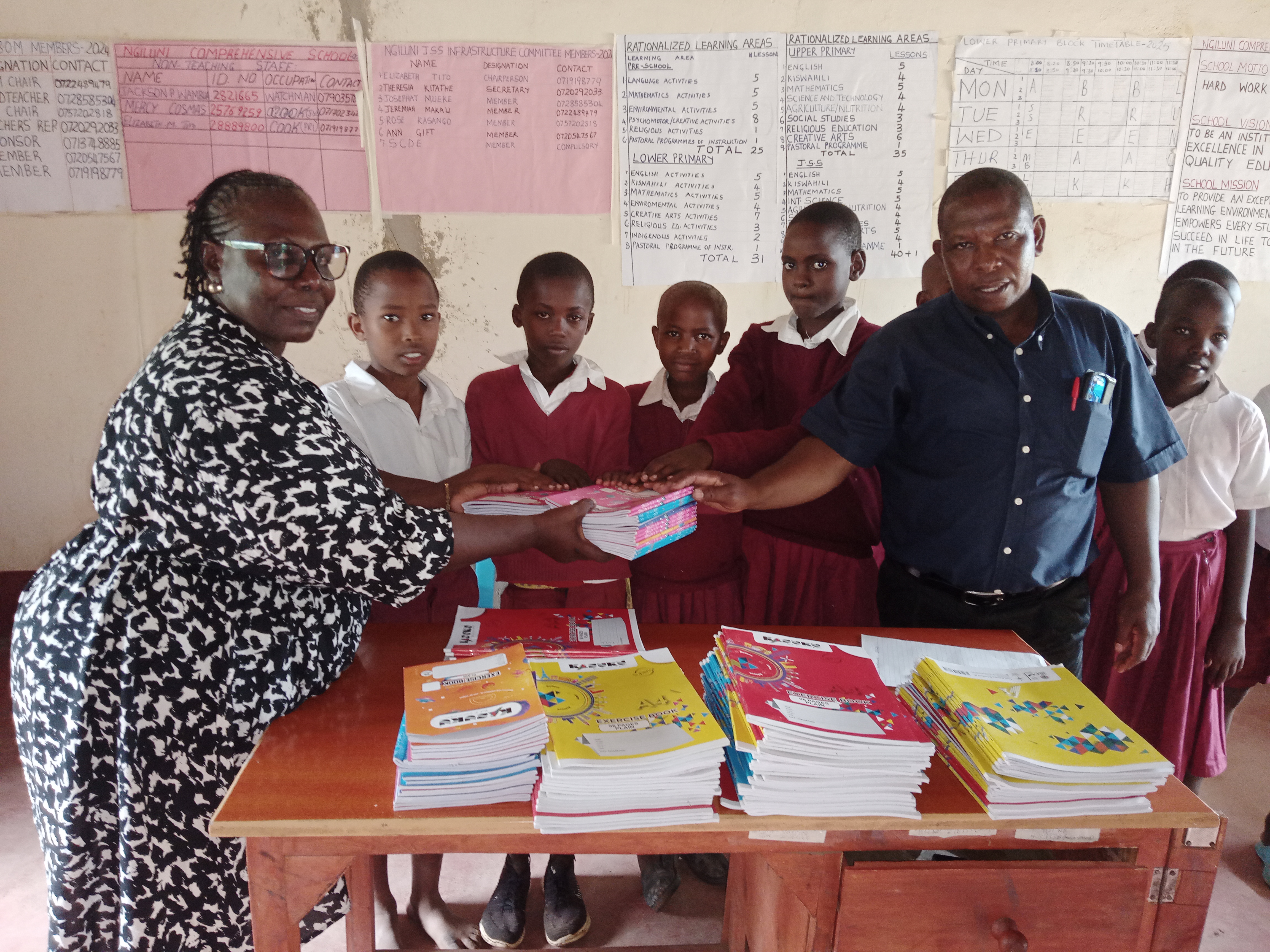Handing over the exercise books to other students by the Secretary, Md Sabina Obura. 